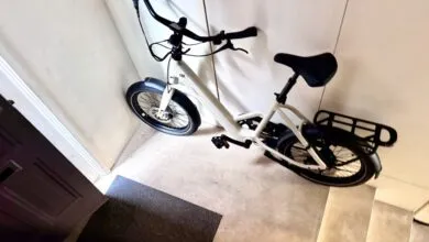 Beige electric bicycle parked indoors against a white wall.