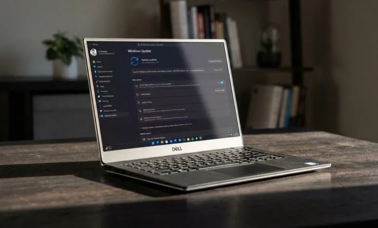 Dell laptop displays Windows Update screen on a wooden desk.