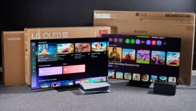 Two OLED TVs displaying game menus, with console boxes behind them.