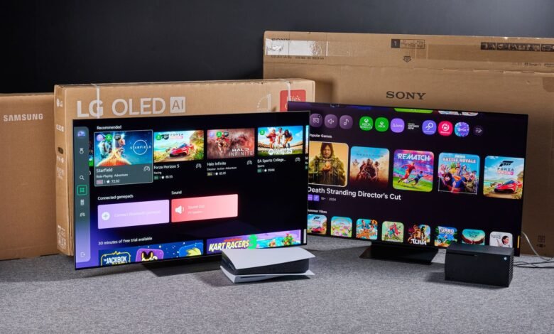 Two OLED TVs displaying game menus, with console boxes behind them.