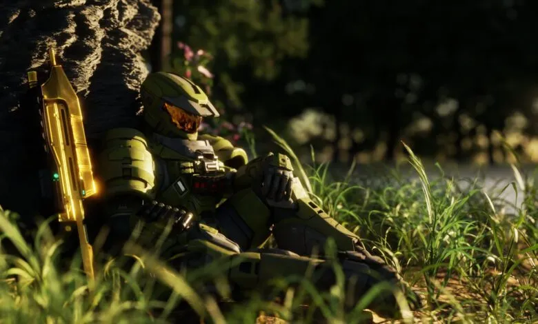 Master Chief rests against a rock with his golden weapon.