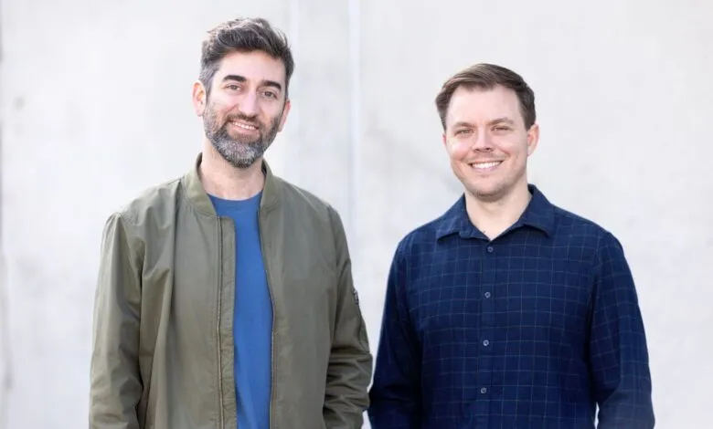 Two smiling men, Jeff Ponchick and Joey Mason, stand side-by-side against a light gray wall.