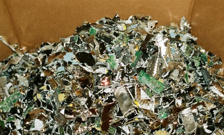 Pile of shredded hard drives and circuit boards in a cardboard box.