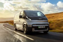 Silver Kia PBV electric van driving on a winding road with golden hills.