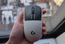 Hand holding a Logitech PRO X SUPERLIGHT 2 gaming mouse, white and black.