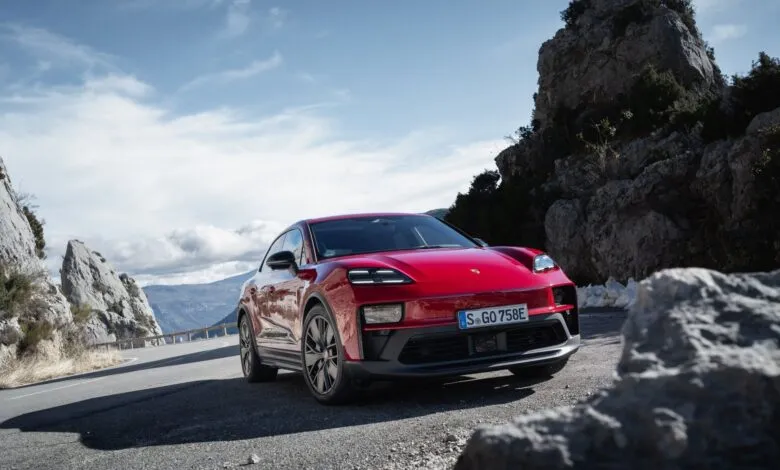 Red Porsche Taycan Cross Turismo driving on a scenic mountain road.