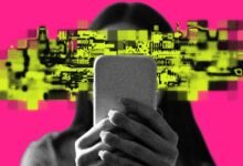 Person holding phone with pixelated face on pink background.