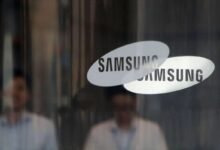 Overlapping Samsung logos on glass with blurred reflections.
