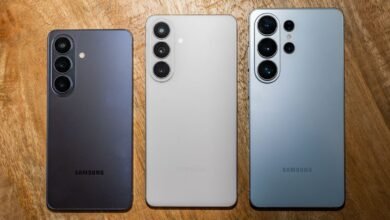 Three Samsung Galaxy phones in different colors on wood surface.