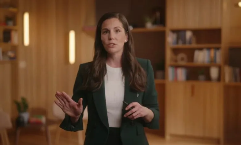 Woman in green blazer presents in modern office setting.