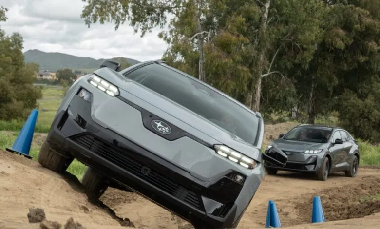 Gray Subaru Solterra SUV navigating a dirt obstacle course, another car follows.