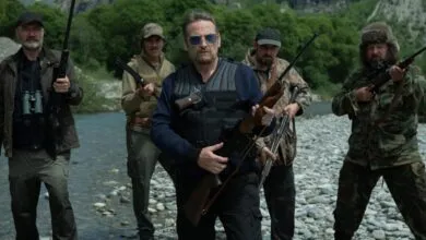 Five armed individuals stand in a river, creating a tense and confrontational scene.