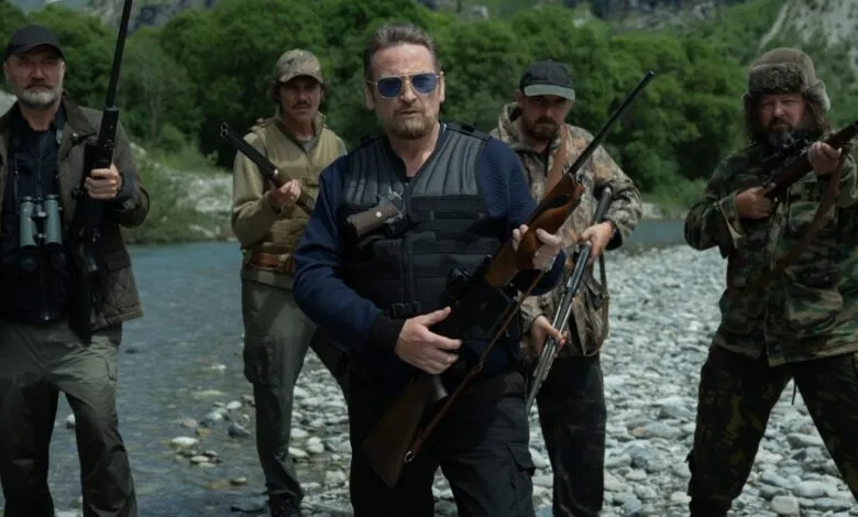 Five armed individuals stand in a river, creating a tense and confrontational scene.