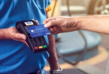 Person paying with a blue VISA credit card at a payment terminal.