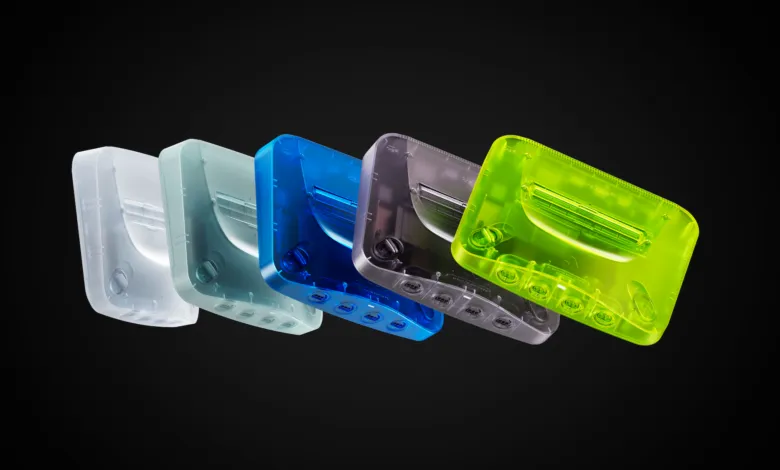 Five translucent Analogue 3D consoles in white, teal, blue, gray, and green.