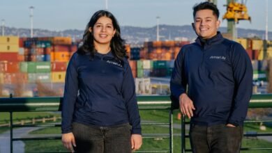 Two Amari AI team members stand outdoors with shipping containers in the background.