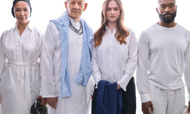 Four people stand together in white clothing against a bright white background.