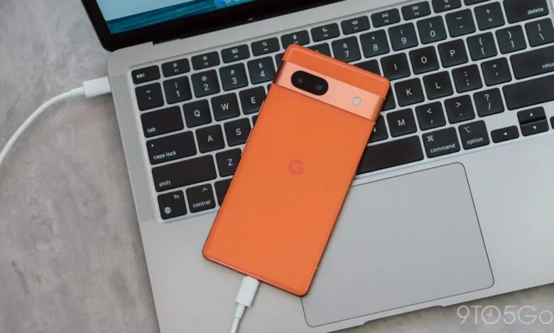 Orange Google Pixel phone charging on a silver MacBook keyboard.