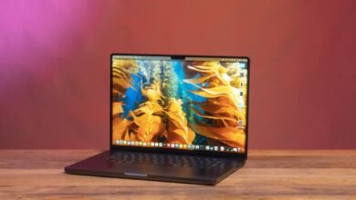 Open 16-inch MacBook Pro on a wooden surface with a kelp forest wallpaper.