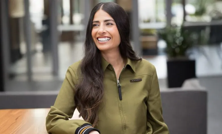 Smiling woman with long dark hair wearing an olive green jacket.