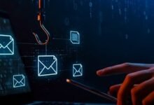 Laptop with email icons, a fishing hook, and a hand holding a phone, representing phishing.