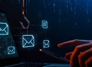 Laptop with email icons, a fishing hook, and a hand holding a phone, representing phishing.