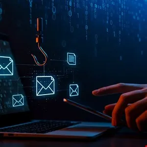 Laptop with email icons, a fishing hook, and a hand holding a phone, representing phishing.