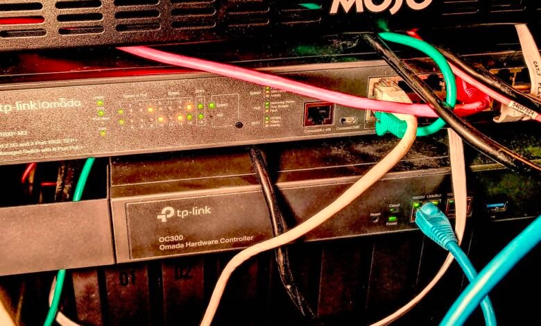 Network rack with TP-Link Omada switch and controller, plus colorful ethernet cables.