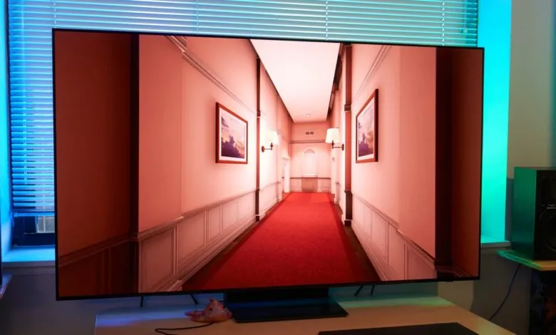 TV displaying a hallway with red carpet and framed pictures on the wall.