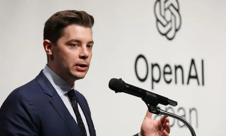 Brad Lightcap of OpenAI speaks at a press conference in front of the OpenAI logo.