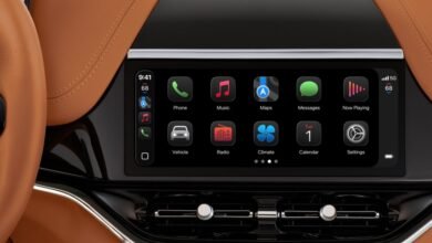Car dashboard display showing Apple CarPlay interface with various app icons.