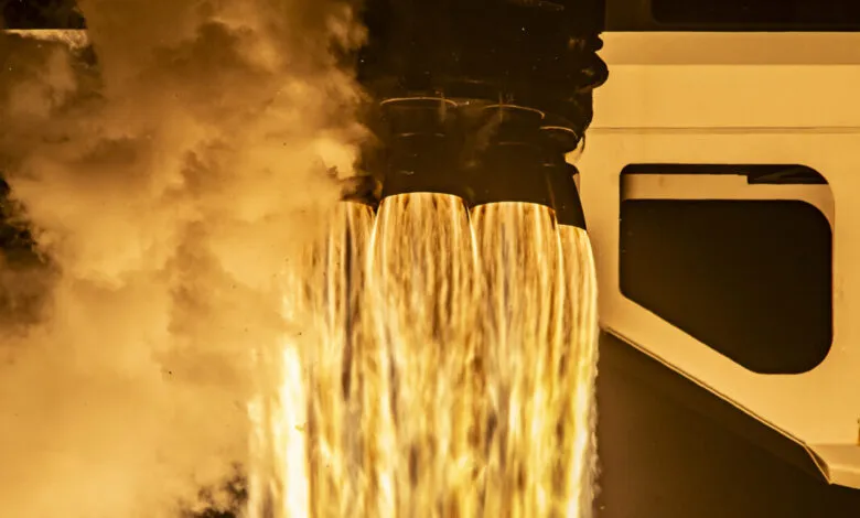 Rocket engine firing with bright flames and smoke during launch.