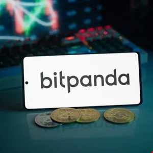 Bitpanda logo displayed on a phone screen with cryptocurrency coins in front.