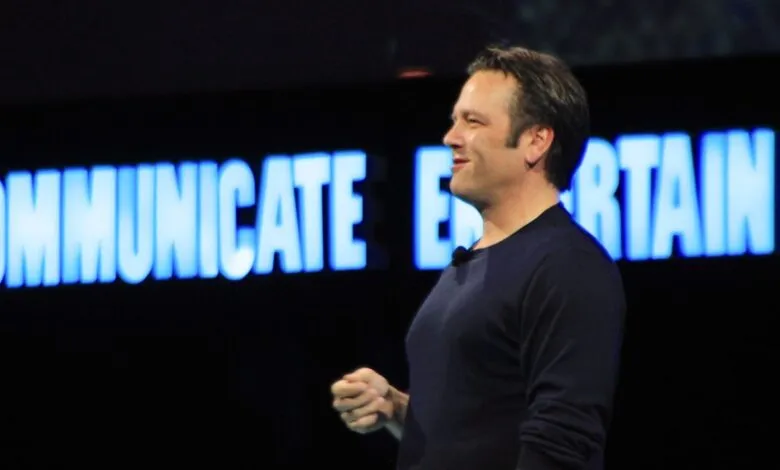 Phil Spencer speaks on stage with 'Communicate Entertain' backdrop.