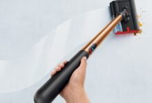 Person cleans wall with Dyson WashG1, removing stains.