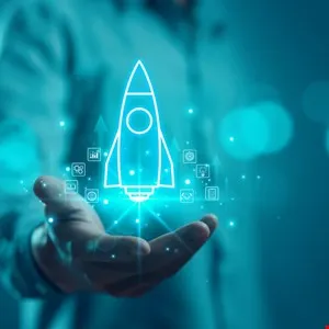 Hand holding glowing rocket icon, symbolizing business startup and growth.