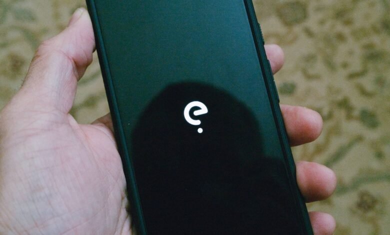 Hand holding a phone displaying the /e/ logo on a black screen.