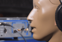 Mannequin head wearing headphones connected to audio equipment.