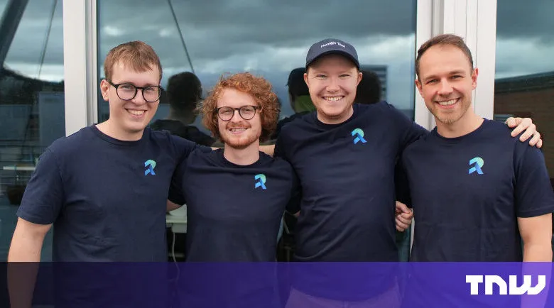 Four smiling men in matching shirts stand together outdoors.