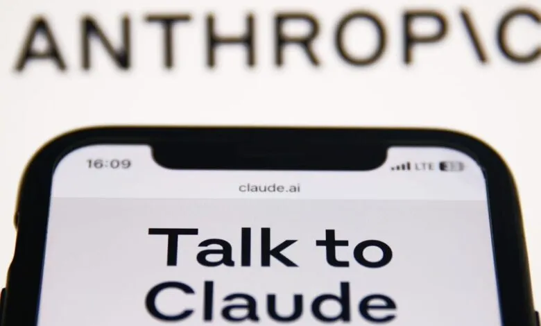 Phone displaying 'Talk to Claude' on claude.ai website, Anthropic logo blurred above.