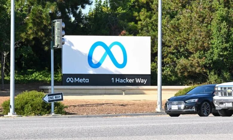 Meta headquarters sign with logo and address, cars parked nearby.