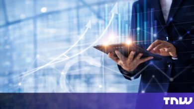 Person in suit using tablet with financial data overlay.