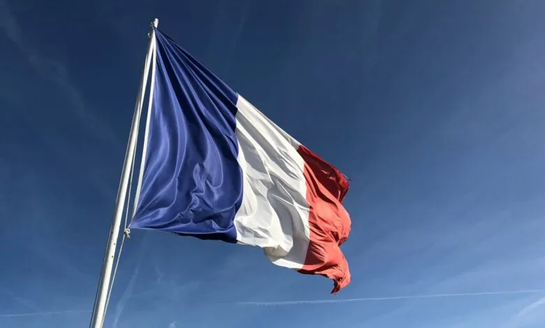 French flag waving against a clear blue sky on a sunny day.