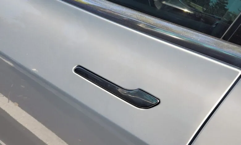 Close-up of a recessed door handle on a silver car.