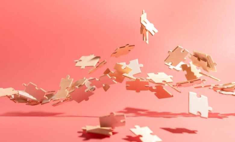 Puzzle pieces floating against a coral pink background.