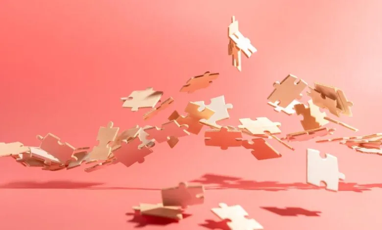 Puzzle pieces floating against a coral pink background.