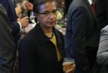 Susan Rice at a gathering, holding a glass of white wine.