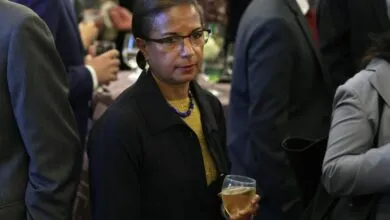 Susan Rice at a gathering, holding a glass of white wine.