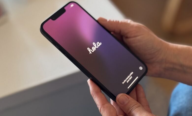 Hands hold smartphone displaying 'hola' on a gradient screen.