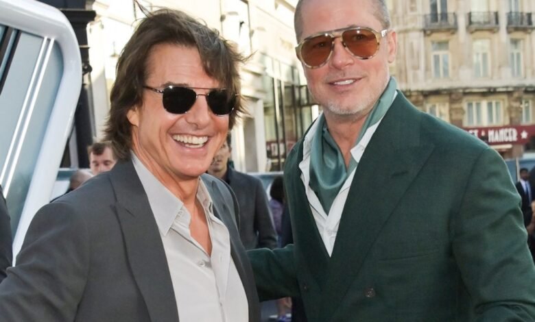 Tom Cruise and Brad Pitt smiling together on a red carpet.